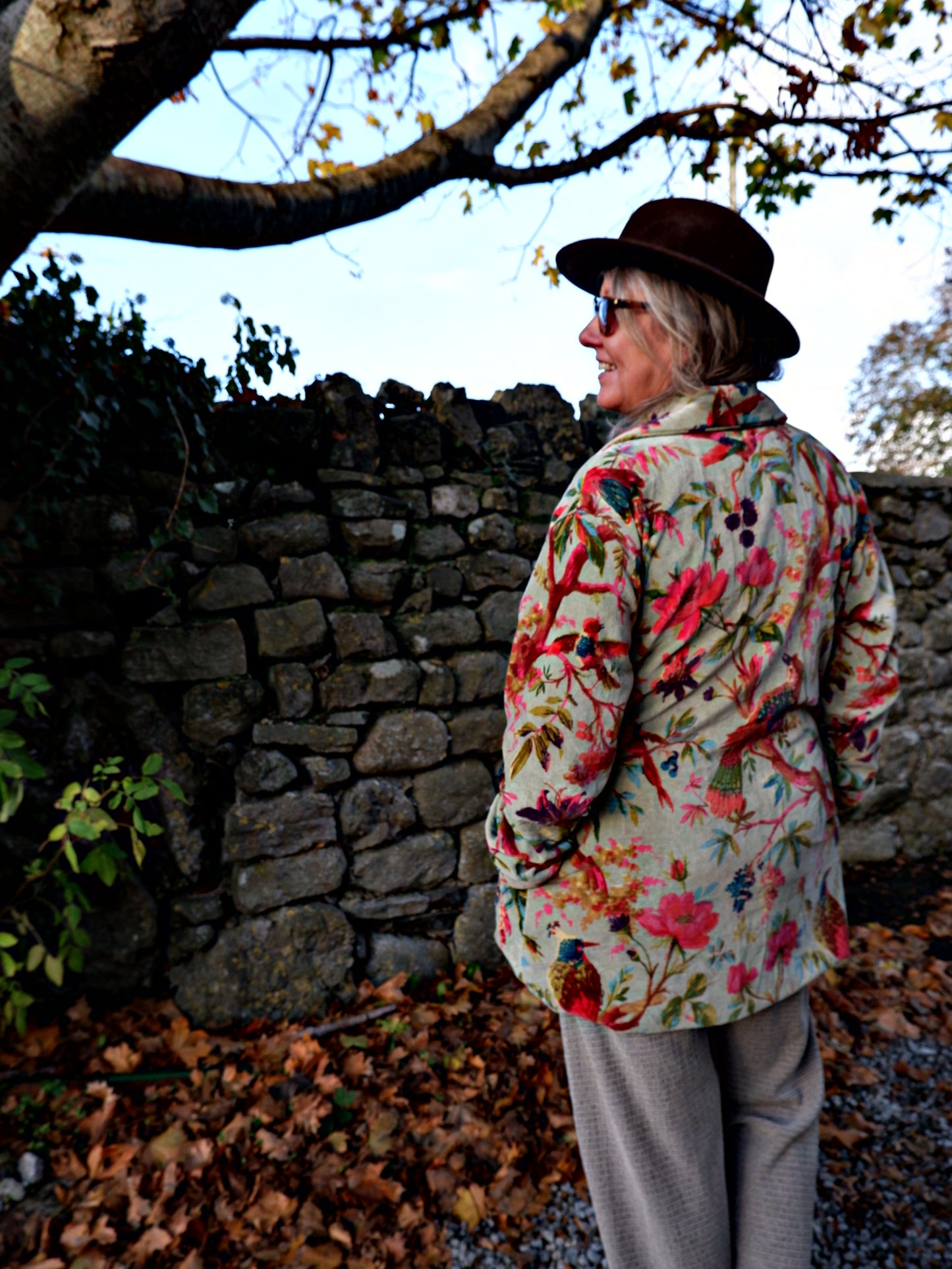Person wearing a colorful floral velvet jacket and hat.